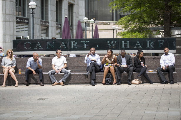 Pracownicy w biurowej dzielnicy Canary Wharf w Londynie jedzą lunch na świeżym powietrzu.