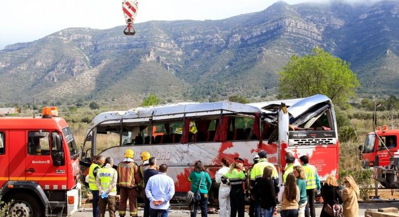 Emergency personnel stand before the righted bus on the Spanish AP-7 motorway following a fatal accident that claimed the lives of 13 foreign students an injured 44 others on March 20, 2016