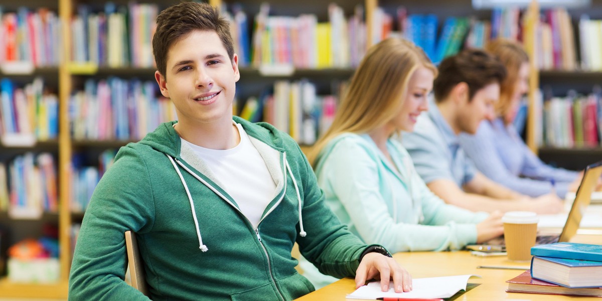 happy student boy reading books in library