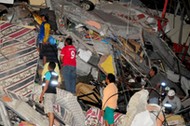 People stand on the debris of a building after an earthquake struck off the Pacific coast in Manta