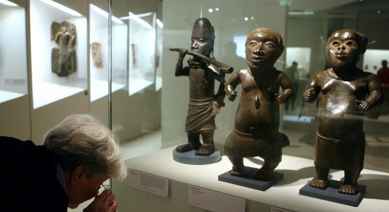 A visitor looks at a statue in brass representing a horn player (L, Benin, South of Nigeria, XVIth and XVIIth Century) during an exhibition focused on refined Art in Benin in 2007 at the Quai Branly museum in Paris