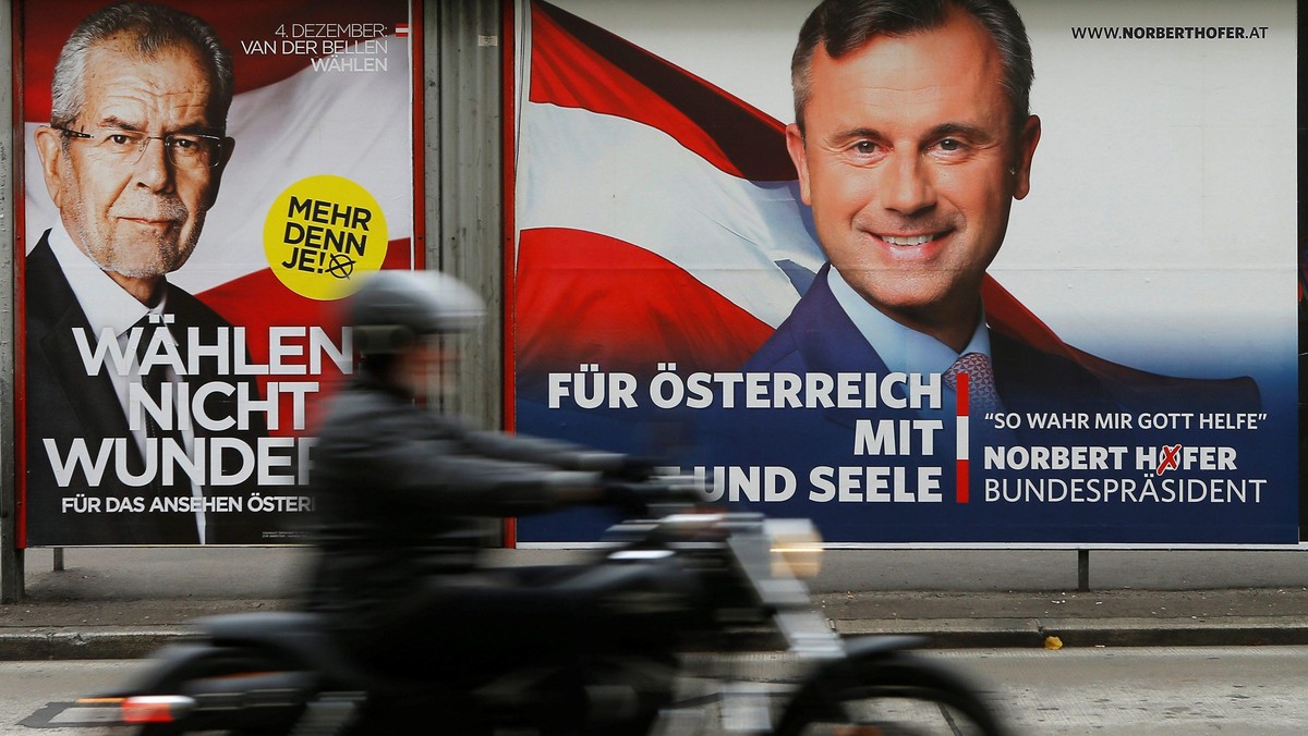 A motorcyclist passes presidential election campaign posters of Van der Bellen and Hofer in Vienna