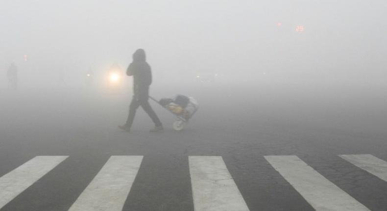 A pedestrian crosses a smog-shrouded street in Lianyungang, eastern China's Jiangsu province on December 19, 2016