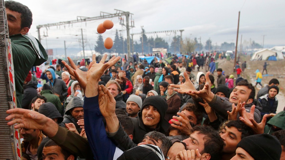 Migrants try to get products from a truck at a makeshift camp on the Greek-Macedonian border near the village of Idomeni