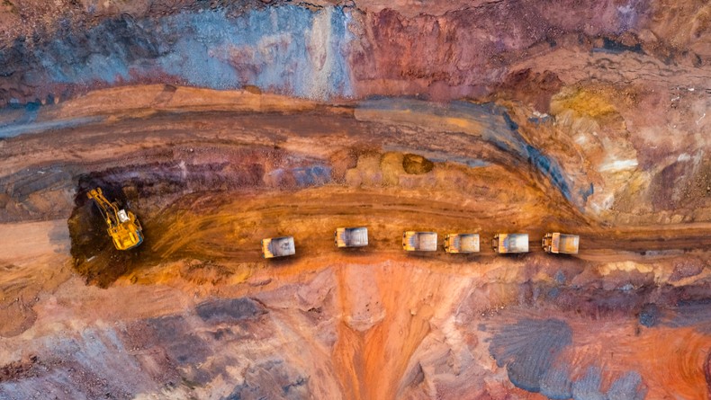 Aerial view of open pit iron ore and heavy mining equipment. Large excavator. [Stock Photo via Getty Images]