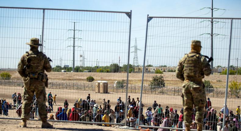 Migrants wait in line adjacent to the border fence under the watch of the Texas National Guard to enter into El Paso, Texas, May 10, 2023.Andres Leighton/AP Photo