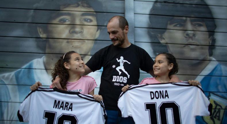Walter Rotundo, a huge fan of the late Diego Maradona, poses with his daughters Mara (L) and Dona (R) Creator: TOMAS CUESTA