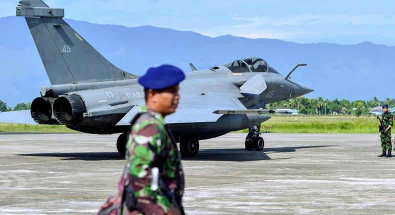 Indonesian soldiers stand guard near one of the seven French fighter jets which were forced to make an emergency landing due to bad weather