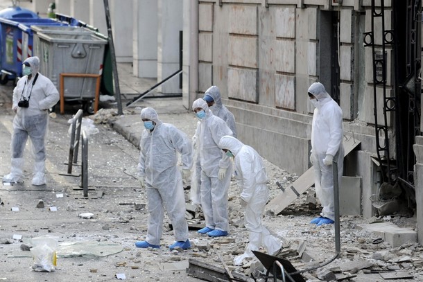 Forensic experts search for evidence on a street where a bomb exploded outside the entrance of the H