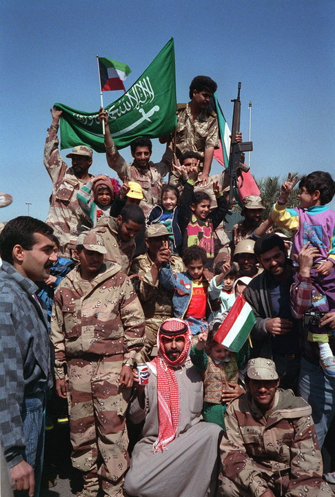 Ludność cywilna i żołnierze koalicji antyirackiej świętują wycofanie się Irakijczyków z Kuwejtu. Widoczne flagi kuwejckie i Arabii Saudyjskiej (fot. CW02 Bailey, domena publiczna).