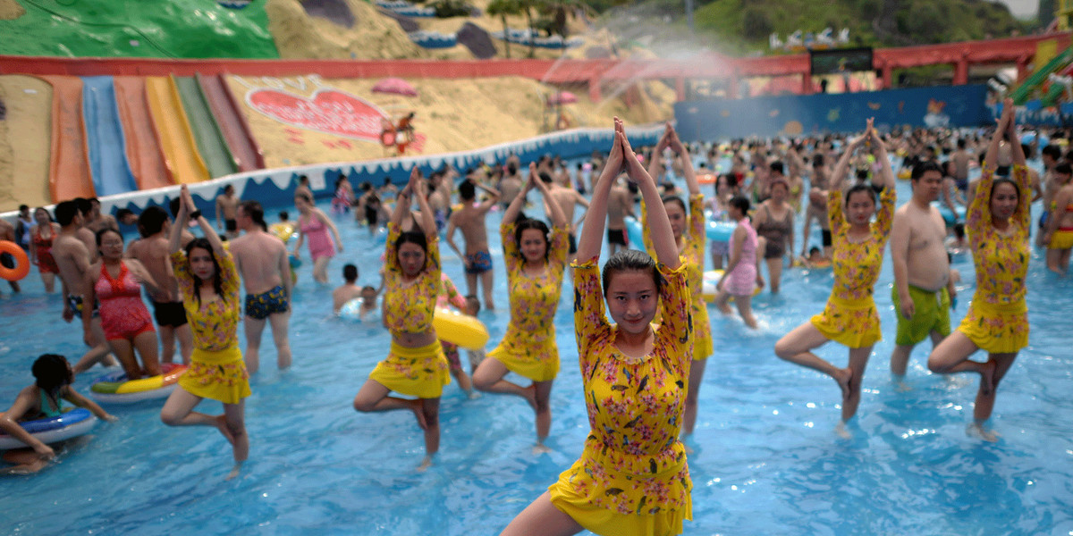 Yoga lovers guide tourists to practice yoga at a water park to cool off in Chongqing, China.