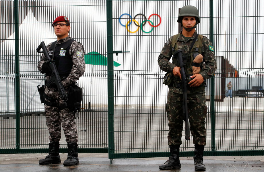 Brazilian Public-Safety National Force, left, and military-police soldiers guard an entrance at the security fence outside the 2016 Rio Olympics Park in Rio de Janeiro, Brazil, July 21, 2016.