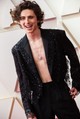 Timothée Chalamet többször is hátat fordított a maszkulin vonalnak. Egy fekete flitteres Louis Vuitton öltönyben érkezett a 2022-es Oscar-gálára, a különleges darab Nicolas Ghesquière tervező munkája, ami a Louis Vuitton 2022-es tavaszi-nyári női kollekciójába tartozik. Az öltönyt elegáns szabása és letisztult vonalvezetése miatt bárki felveheti, ezzel pedig Chalamet bebizonyította, hogy a divat nem a nemek meghatározásáról szól. Ami a Cartier ékszereket illeti, a fehérarany gyűrű és nyaklánc volt az outfit stílusos megkoronázása.
