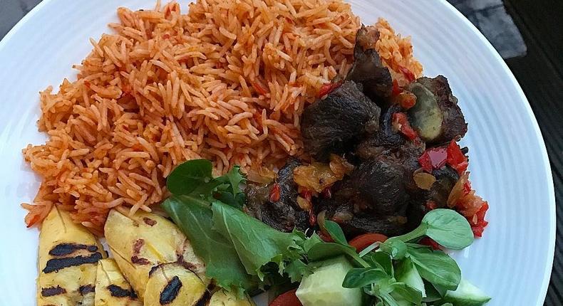 Coconut jollof rice, served with fried goat meat, grilled plantain and some leafy vegetables (Foodace)