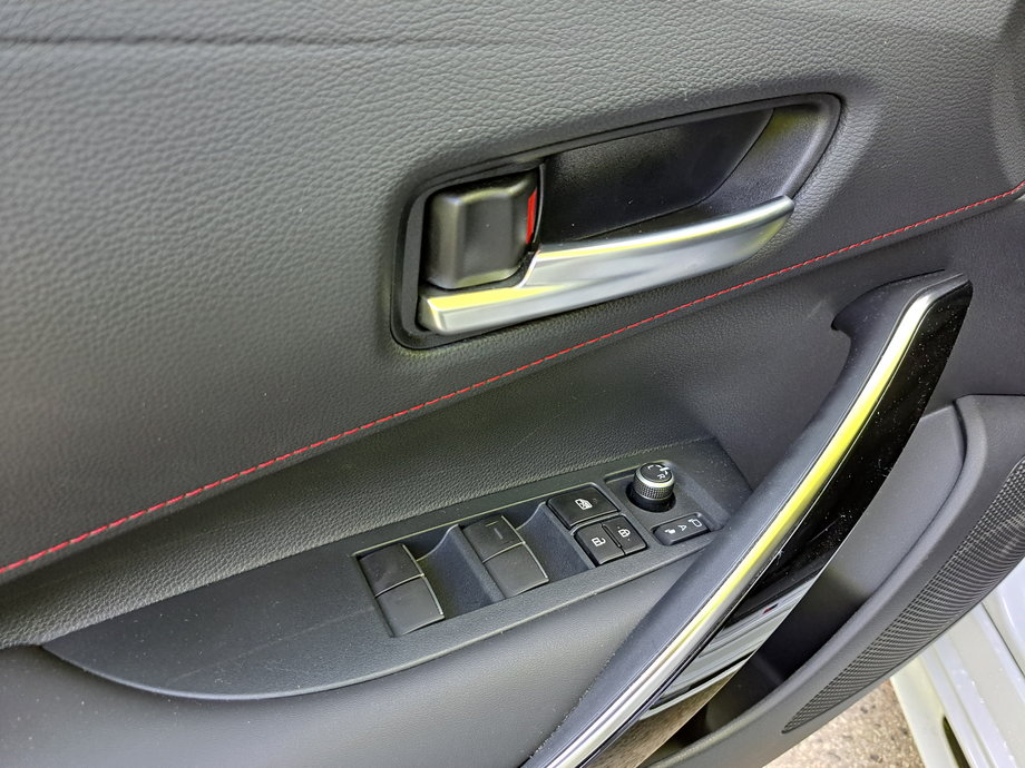 Toyota Corolla Hybrid Touring Sports - czerwone przeszycia mamy na boczkach drzwi, fotelach, czy też w okolicach dźwigni automatycznej skrzyni.