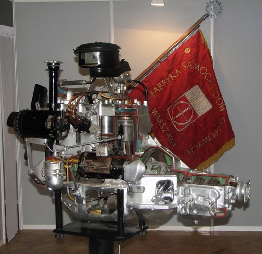 Jednostka napędowa Warszawy - silnik dolnozaworowy. W tle sztandar Fabryki Samochodów Osobowych FSO