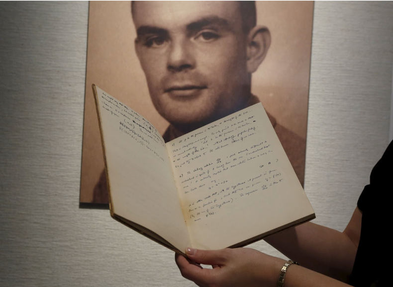 Notebook of Alan Turing is displayed in front of a photo of him. Picture: REUTERS/Bobby Yip