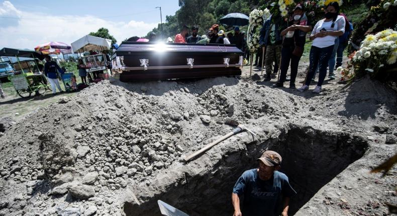 A grave is dug while a family waits during a funeral for a COVID-19 victim at the San Miguel Xico cemetery in Mexico