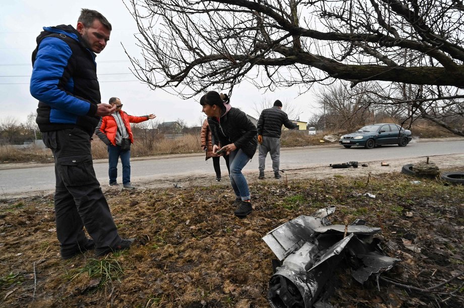 Ludzie fotografują pozostałości po rakiecie w dzielnicy mieszkalnej Kijowa, 25 lutego 2022 r.