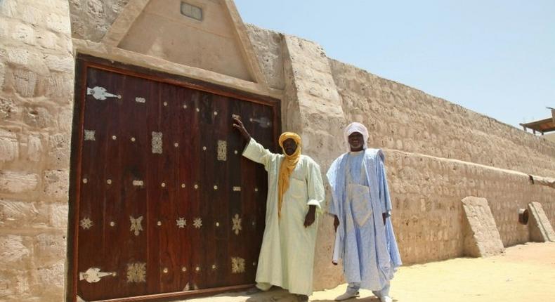 Workers pose in front of the newly restored doors of the 15th-century Sidi Yahia mosque hacked apart by jihadists in Mali's ancient city of Timbuktu four years ago