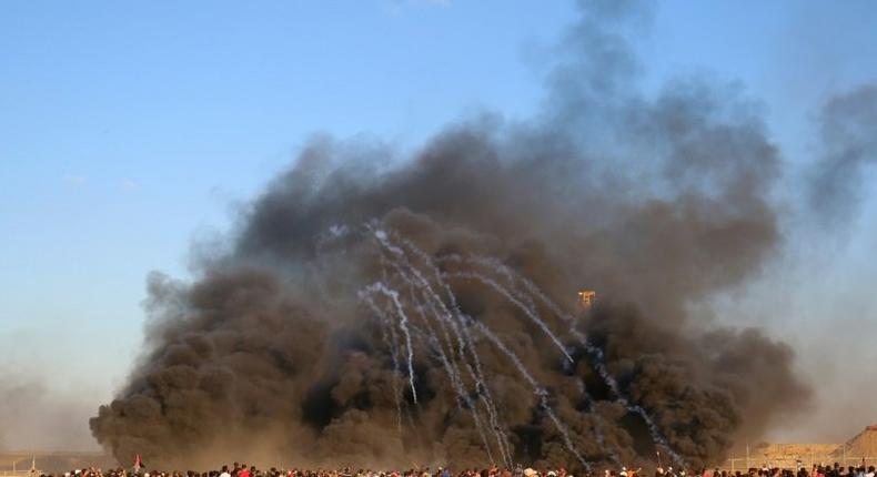 Palestinians protest along the Israel-Gaza border on September 14, 2018 as Israeli forces fire tear gas canisters through smoke from burning tyres