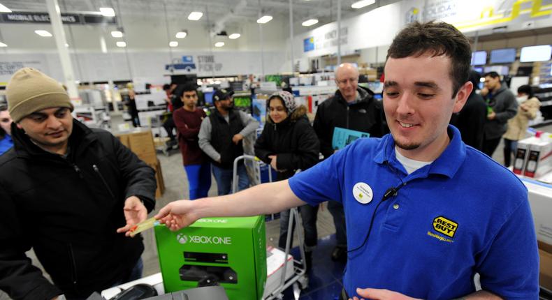 Just after midnight, Best Buy employee Christopher Gervais, right, hands back a credit card after he rang up a Xbox One game set.