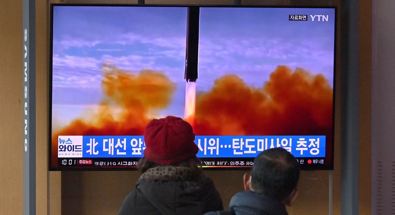 People watch a television screen showing a news broadcast with file footage of a North Korean missile test, at a railway station in Seoul on March 5, 2022.