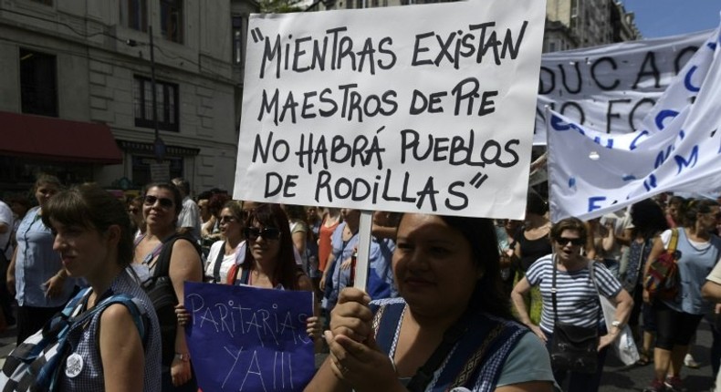 A teacher holds a placard reading While there are teachers standing, there will be no people on their knees during a 48-hour nationwide strike demanding pay rises, in Buenos Aires on March 6, 2017