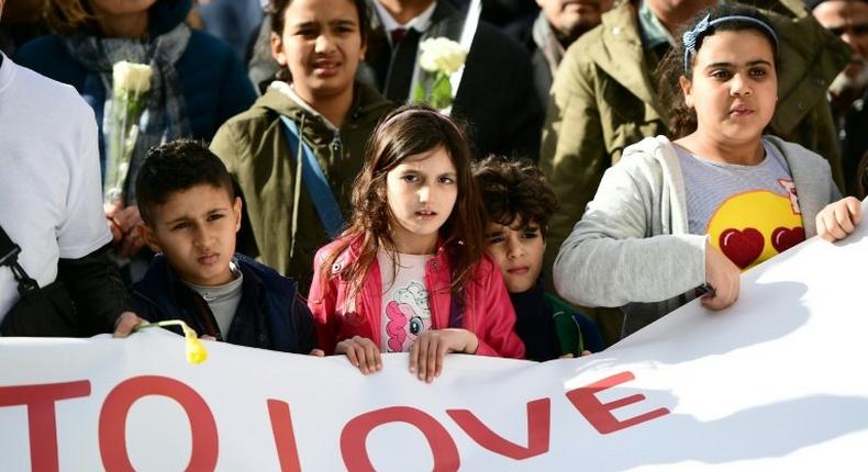 Children carry a banner during a commemorative march as Belgium marks the first anniversary of the twin Brussels attacks by Islamic extremists on March 22, 2017 in Brussels