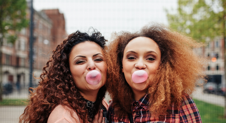 women chewing gum blowing bubbles happy hugging friends shutterstock_314302964