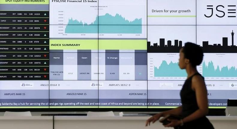 A worker walks past an electronic board displaying movements in major indices, at the Johannesburg Stock Exchange in Sandton, February 12, 2015. REUTERS/Siphiwe Sibeko