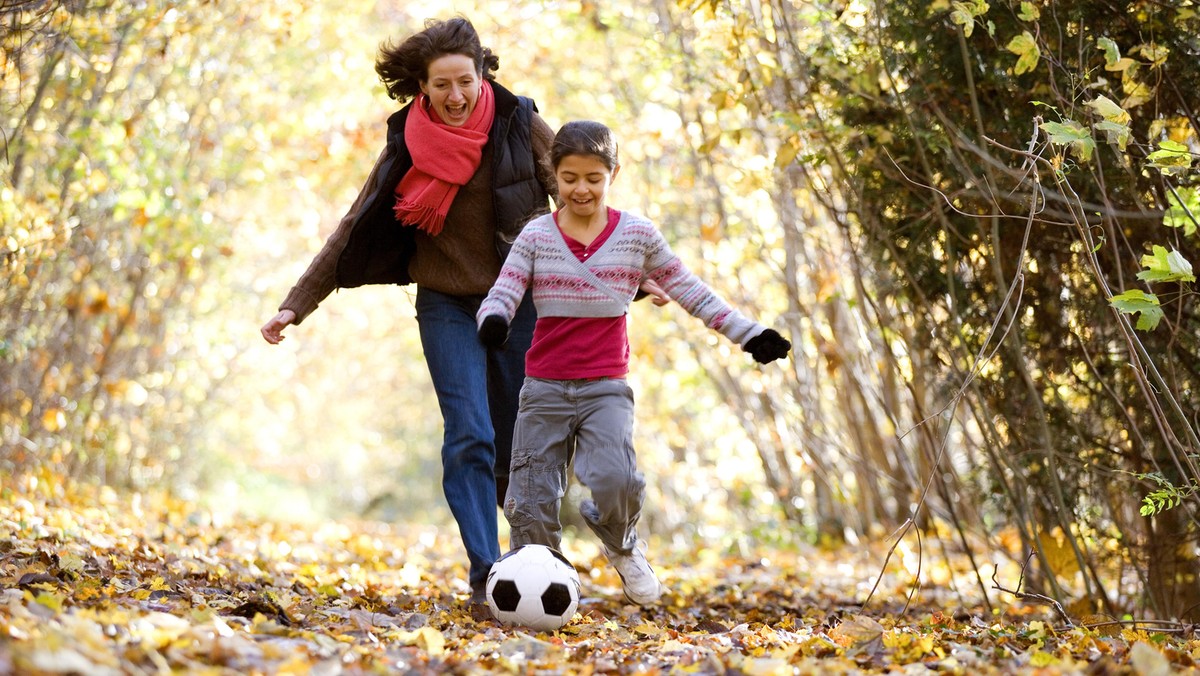 Mid adult woman and her daughter playing with a soccer ball