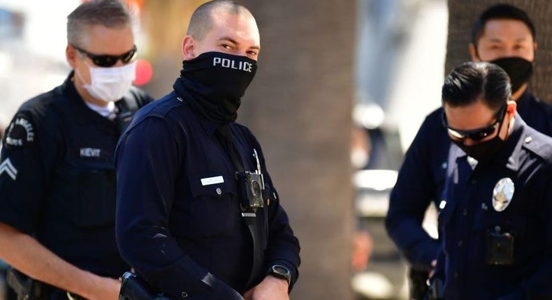 Los Angeles Police Department (LAPD) officers wear facial covering while monitoring an Open California rally in downtown Los Angeles, on April 22, 2020. - Over the past week there have been scattered protests in several US states against confinement measures, from New Hampshire, Maryland and Pennsylvania to Texas and California.
