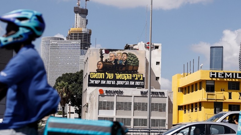 Volebný billboard proti izraelskému premiérovi Benjaminovi Netanjahuovi, na ktorom sú Sara, Jair a Benjamin Netanjahu s textom v hebrejčine, podľa ktorého je Netanjahu stroj Hamasu, ktorý zničil Izrael (v Tel Avive v Izraeli 17. augusta 2026).