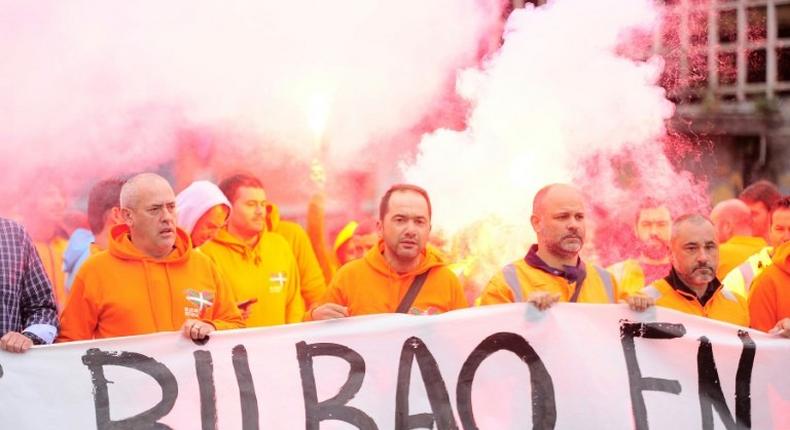 Bilbao's dockers hold a banner with flares in background during a two-day strike at the Port of Bilbao, in the Spanish Basque city of Santurtzi on June 15, 2017