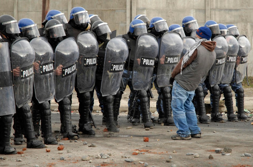 A protester urinates in front of a row of policemen during riots following the death of a 15-year-old boy in San Carlos de Bariloche June 18, 2010.