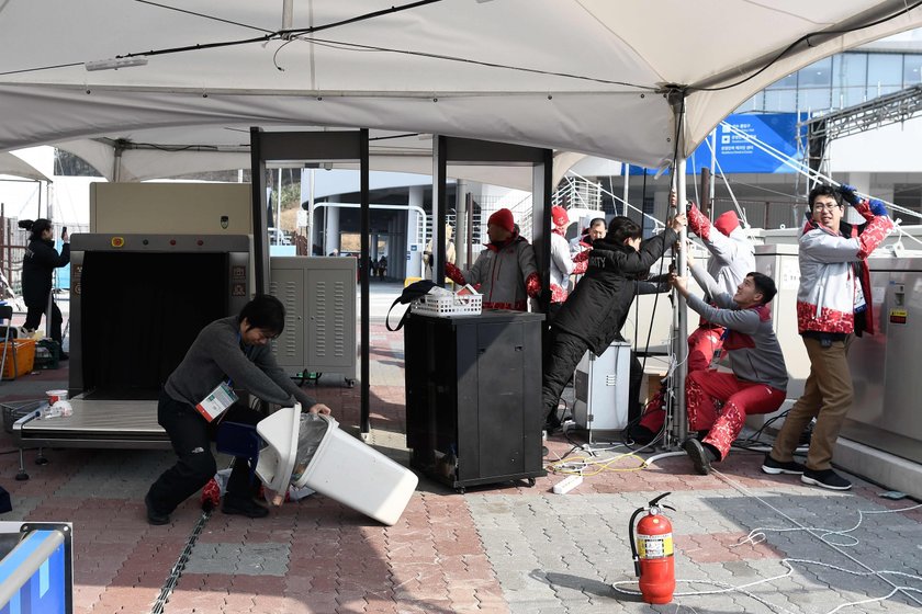 Firefighters assess the damage to a food stall that was blown over by the wind