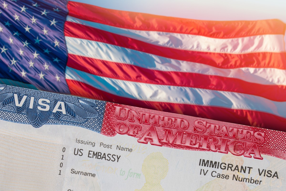 Amerykańska flaga oraz fragment wizy imigracyjnej do USA – symbol tematu deportacji i polityki imigracyjnej Stanów Zjednoczonych.