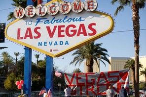 People sign a banner near the Welcome to Fabulous Las Vegas sign following the Route 91 music fest