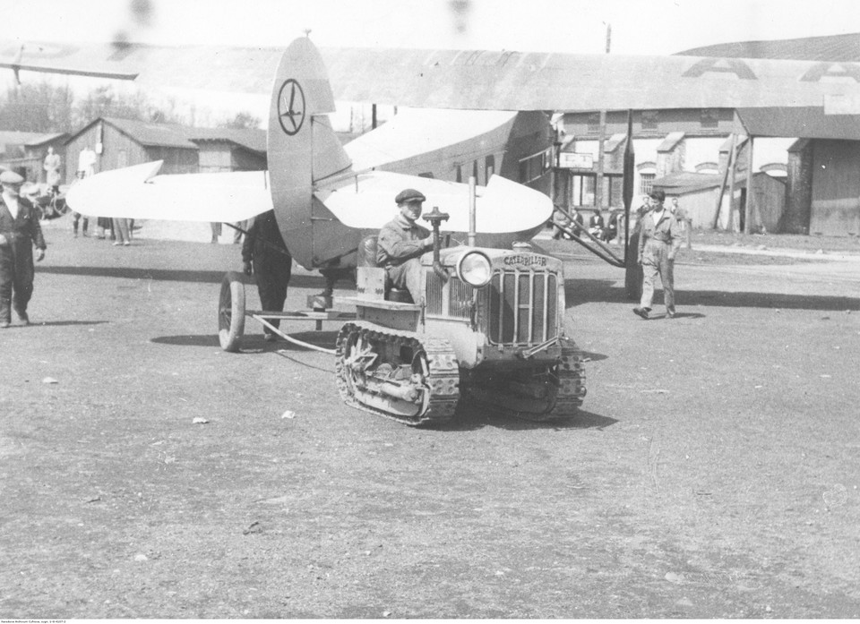 Ciągnik gąsienicowy marki Caterpillar wprowadzający do hangaru samolot pasażerski typu Fokker F-VII/1m