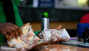 A bank clerk cheking old-issue currency bills received from a client to exchange for new-issue tender at a branch of a local bank in the Kenyan capital, Nairobi, September 30, 2019. - Kenya demonetized it's old-series tender at midnight tonight in favour of new currency notes, a move intended to curb laundering of money acquired through corruption, especially in government accounting, that is rampant in the East African nation.  (Photo by TONY KARUMBA/AFP via Getty Images)