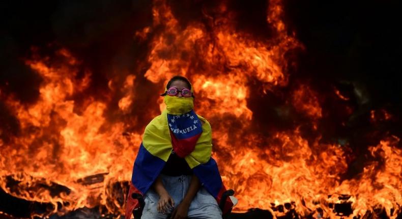 A Venezuelan opposition activist is backdropped by a burning barricade during a demonstration against President Nicolas Maduro in Caracas, on April 24, 2017