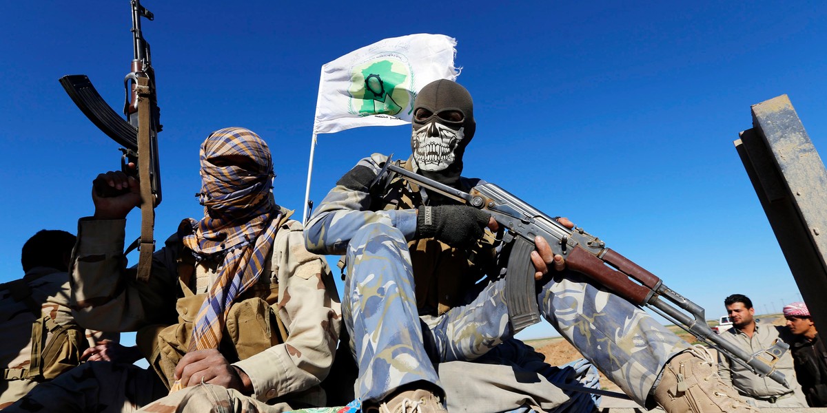 Masked Shi'ite fighters hold their weapons in Al Hadidiya, south of Tikrit, en route to the Islamic State-controlled al-Alam town, where they are preparing to launch an offensive on Saturday, March 6, 2015.