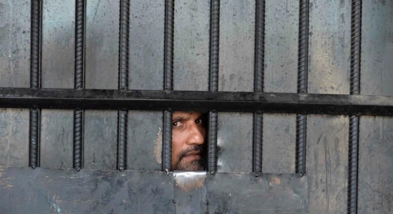 A man watches from behind a closed gate after a raid at the prison in Jalalabad