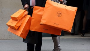 A couple walk with Hermes shopping bags as they leave an Hermes store in Paris March 21, 2013. Hermes on Thursday said operating margin last year reached its highest level since the French luxury group listed in 1993 on robust demand for its hand-crafted leather goods and printed silk scarves. REUTERS/Philippe Wojazer