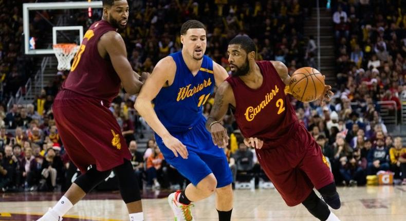 Kyrie Irving (R) of the Cleveland Cavaliers drives around Klay Thompson of the Golden State Warriors during the second half, at Quicken Loans Arena in Cleveland, Ohio, on December 25, 2016