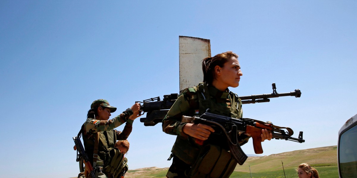 Yazidi female fighter Asema Dahir (L), 21, holds a weapon as she rides a pickup truck during a deployment near the frontline of the fight against Islamic State militants in Nawaran near Mosul, Iraq, April 20, 2016.