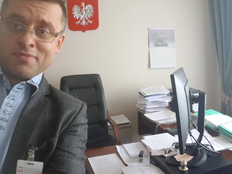 Selfie z grupy Kasta. Sędzia Arkadiusz Cichocki, w tle zielone teczki 