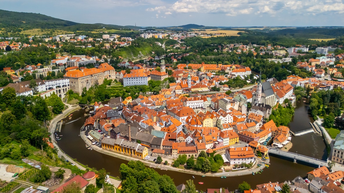 Ikonická silueta Českého Krumlova so zámkom a Kostolom svätého Víta z vtáčej perspektívy.
