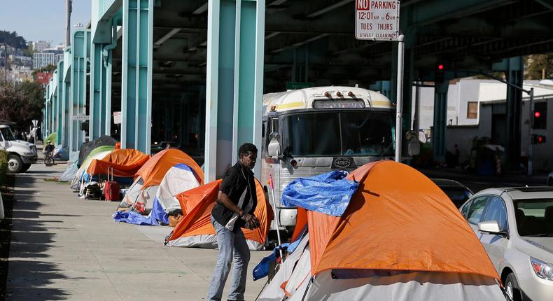 A man stands outside his tent on Division Street in San Francisco.